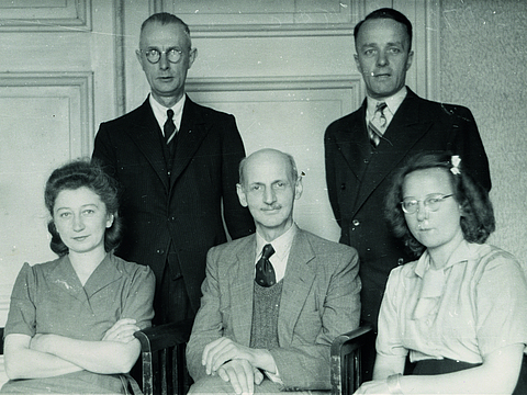 Das Foto zeigt fünf Erwachsene, die in die Kamera schauen. Ein Mann und zwei Frauen sitzen nebeneinander, zwei Männer stehen hinter ihnen.